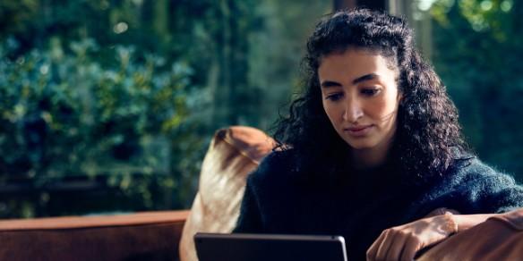 Frau mit Tablet auf Couch sitzend